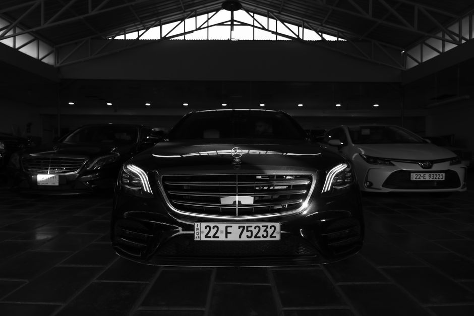Black and white image of luxury cars in a showroom, featuring a prominent front view.